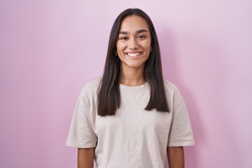 Wall Mural - Young hispanic woman standing over pink background with a happy and cool smile on face. lucky person.