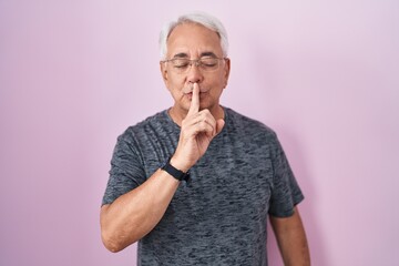 Sticker - Middle age man with grey hair standing over pink background asking to be quiet with finger on lips. silence and secret concept.