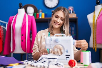 Canvas Print - Young caucasian woman tailor smiling confident using sewing machine at sewing studio