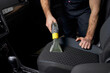 © Roman - Details of car vacuum cleaning. Professional cropped male worker using wet vacuum cleaner for dirty car interior. Auto car service cleaning the drivers seat, cleaning and vacuuming concept