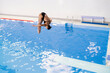 girl doing extreme tricks jumping into water, spring-board diving championships