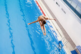 Fototapeta Tęcza - olympic sport, sports diving in the swimming pool, female athlete doing spin in the air