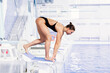 olympic sportswoman standing on the starting point in the swimming pool