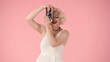 © kinomaster - Woman taking pictures on old camera. Woman looking like in studio on pink background close up.