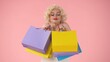 © kinomaster - Young happy woman holding colorful shopping bags. Woman looking like in studio on pink background. Shopping concept, sales, black Friday.