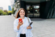 © mdyn - Young happy businesswoman smiling and using smart phone at the city. Beautiful woman on the way to the office searching information on the internet with smartphone. Check social networks or book hotel