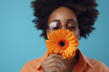 Young African American Woman With A Gerbera Flower Near Her Face, Blue Background. Generative AI