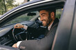 © Yaroslav Astakhov - Male driver in suit is riding behind steering wheel of car and looks away. High quality photo