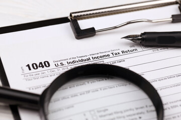 Wall Mural - Form 1040 US Individual Income Tax Return on A4 tablet lies on office table with pen and magnifying glass close up