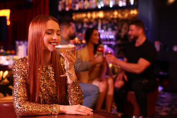 Canvas Print - Friends spending time together in bar. Beautiful woman with fresh alcoholic cocktail at table, space for text