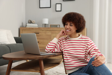 Poster - Beautiful young woman using laptop at wooden coffee table in room