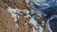 A Drone View Of A Herd Of Mountain Goats Running The Steep Slope.Wild Mountain Goats On Rugged Cliffs On A Snowy Day.They Climb The Steep Cliff.Mountain Goats Living In Mountainous.Great Natural View.