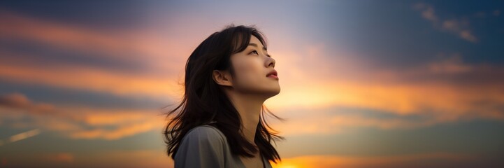 Poster - Young Asian woman looking at sunset sky