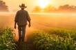 © MVProductions - Rear view of a farmer at dawn while walking through a dew-kissed corn field towards distant grain silos, depicting rural life and agriculture