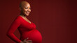 happy poc bald pregnant woman holding belly wearing tight dress isolated on red studio background with copy text space