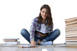© ty - Young female student studying at home, writing article for publication, sitting on floor on a transparent background surrounded with pile of books.