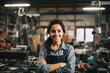Portrait of a female engineering student in a workshop looking at the camera smiling - education concepts