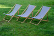 Stare drewniane leżaki plażowe na trawniku w ogrodzie 