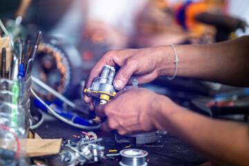 Wall Mural - Selective focus to hand of an electric motor repairman. Mechanic is repairing an electric motor by replacing the copper coil. Electric fan motor repair work .