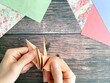 折鶴を持つ日本人女性の手元と机上の折紙