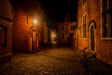 Residential Student Houses In The Groot Begijnhof Historic District Of Leuven At Night With Streetlamp Light. Atmospheric Street Photography Showing Old Stone Roads With Pretty Red Brick Buildings
