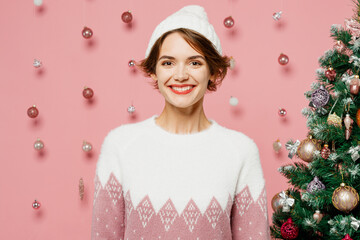 Wall Mural - Merry smiling cheerful satisfied fun cool young woman wear white sweater hat posing looking camera isolated on plain pastel pink background studio Happy New Year celebration Christmas holiday concept