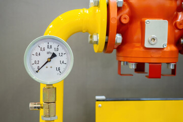 Wall Mural - Gas equipment with manometer. Mechanical sensor indicates lack of pressure in pipes. Yellow-red pipe near wall. Gas technologies. Industrial boiler equipment. Gas compressor mechanism