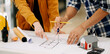 © Nuttapong punna - Creative architect projecting on the big drawings with architectural project at construction site at desk