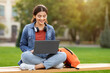 © Prostock-studio - Indian young woman student sitting on bench working on laptop