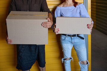 Woman with neat manicure and man are standing near yellow container