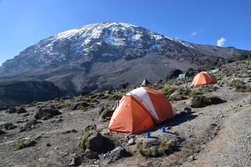 camping in an orange tent on the lemosho route while trekking mount kilimanjaro in tanzania