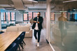 © BullRun - Confident businessman walking in modern office with laptop