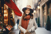 Young happy smiling woman in winter clothes at street Christmas market in Paris. Christmas shopping. concept, holding gift box.