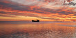 View of a red and orange fiery sunset reflected in The Ocean at Heron Island with a shipwreck in the distance, Great Barrier reef, Queensland, Australia
