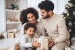 Mixed race family mother, father and child unpacking Christmas gift box together