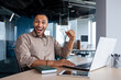© Liubomir - Successful Indian programmer celebrating successful completion of testing new software, man looking at camera, satisfied with achievement results, working with laptop, inside office, online winner.