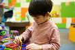 © Jonh_Walker - A little Asian boy is playing with a square magnetic puzzle.