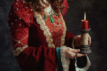 Wall Mural - Closeup on medieval queen in red dress with candle