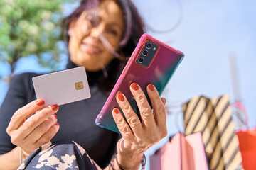 Close up shot of woman hand holding credit card and using smartphone for online shopping. blank credit card for copy space