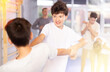 © JackF - Focused kids in pair exercising self-defense movements during group class in modern sports studio, closeup