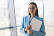 © BullRun - Smiling focused woman standing with tablet in office