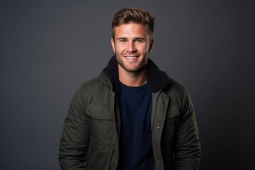 Portrait of a handsome young man smiling at the camera on a dark background