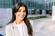 © Xavier Lorenzo - Portrait of young executive businesswoman smile at camera standing outside over modern company office building