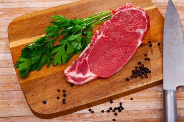 Wall Mural - Raw piece of beef tenderloin with spices on wooden cutting board on light background. High quality photo