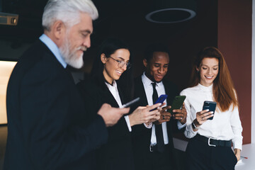 Wall Mural - Cheerful multiethnic colleagues using smartphones in office