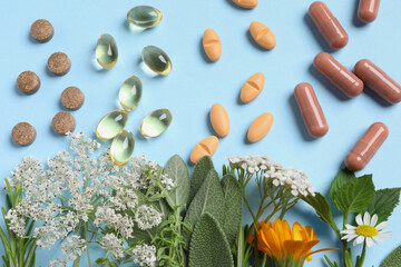 Wall Mural - Different pills, herbs and flowers on light blue background, flat lay. Dietary supplements