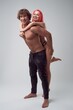 Happy topless woman trying to climb a muscled man's back