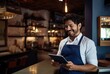 Man in a blue apron smiling with a tablet.