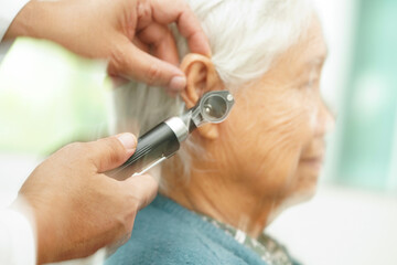 Wall Mural - Otolaryngologist or ENT physician doctor examining senior patient ear with otoscope, hearing loss problem.