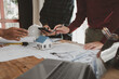 © Chadaporn - Architects and engineers work together to come up with solutions to house building problems, The property is about to be designed by a group of engineers, Architects are reviewing plans together.